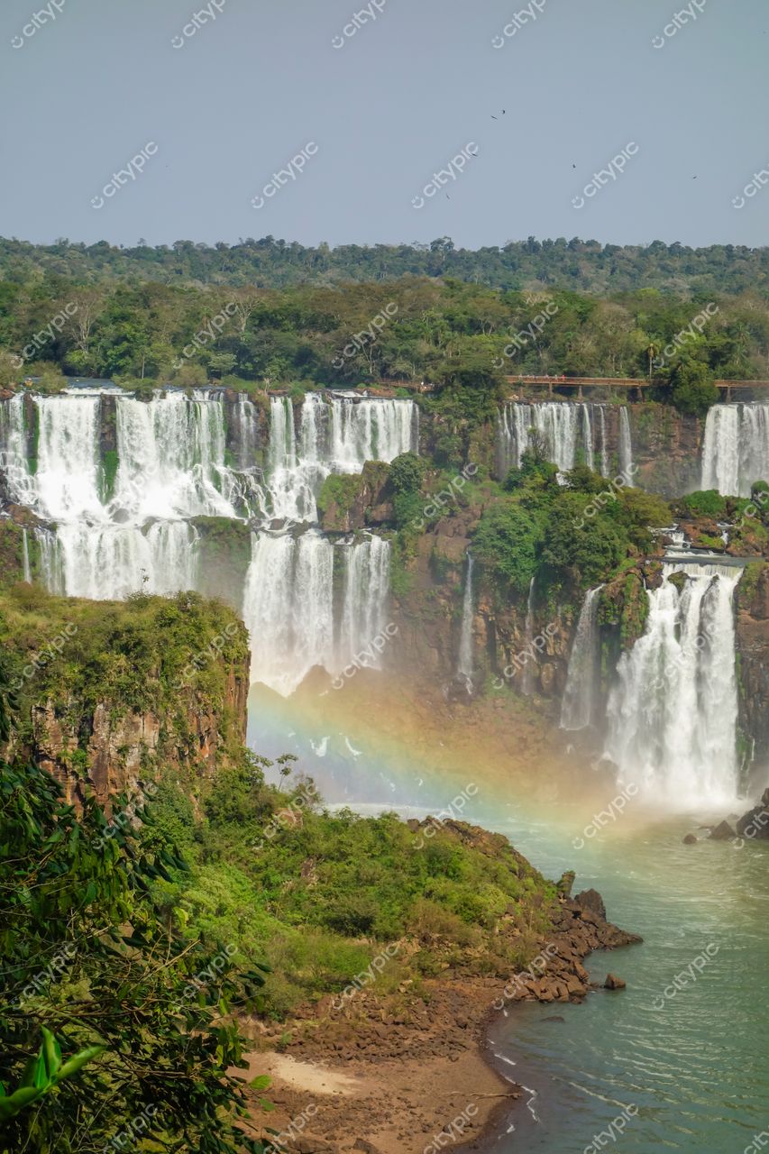 Foz do Iguaçu, Paraná vista panorâmica das Cataratas com arco-íris e vegetação densa sob céu claro durante o dia
