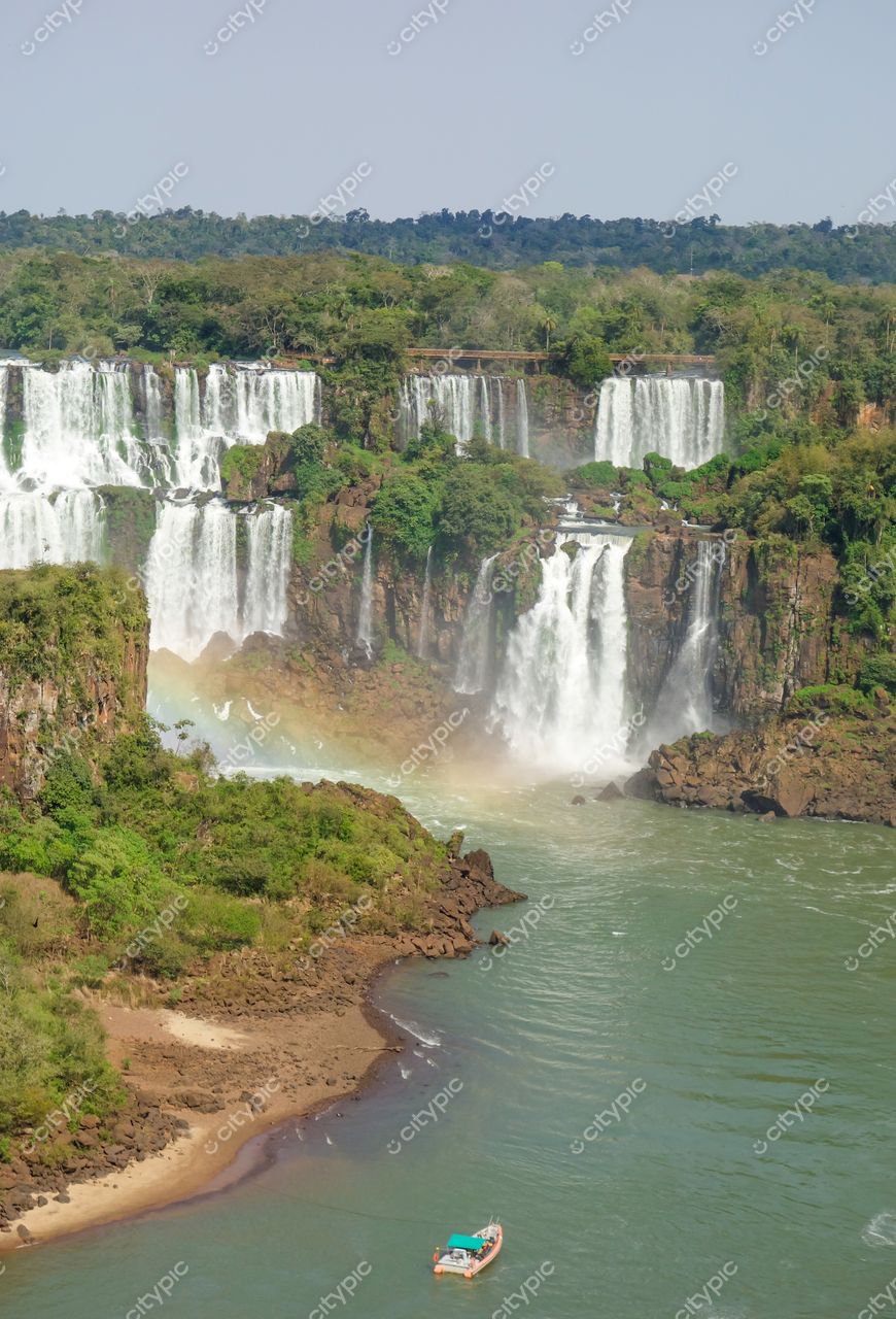 Foz do Iguaçu, Paraná, barco em primeiro plano com sol iluminando as cataratas e vegetação tropical exuberante