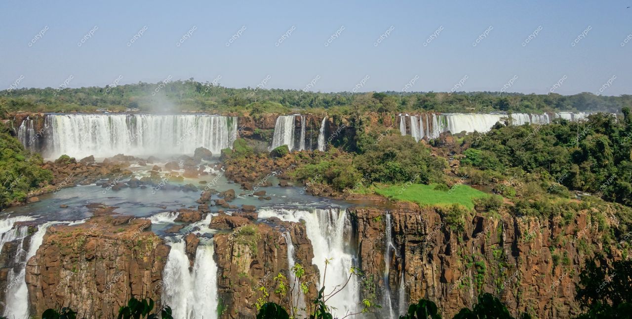 Foz do Iguaçu, Paraná, Cataratas do Iguaçu em dia ensolarado com vegetação densa e céu azul claro