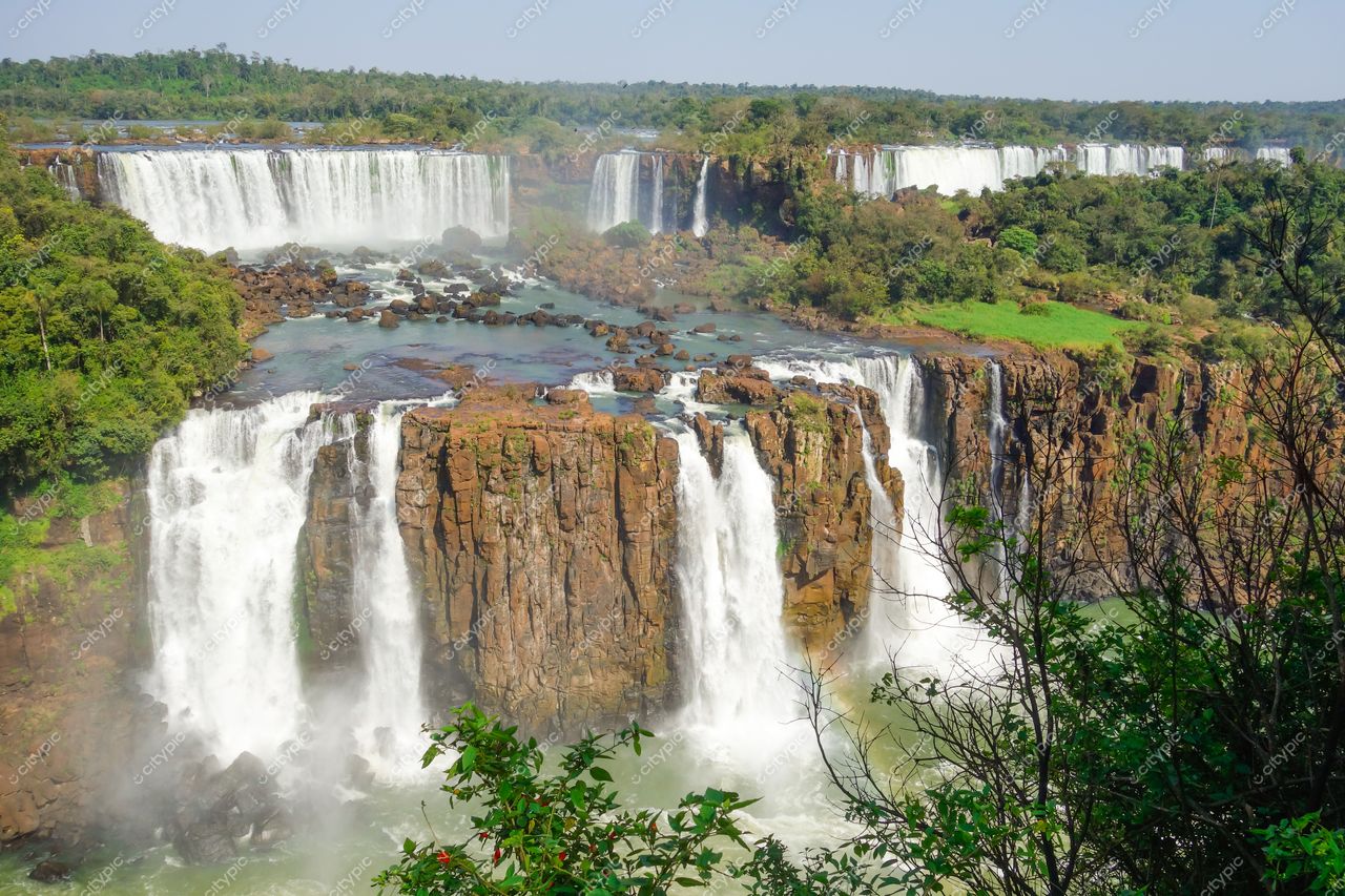 Foz do Iguaçu, Paraná, Cataratas do Iguaçu em dia ensolarado com vegetação densa e rochas expostas ao redor