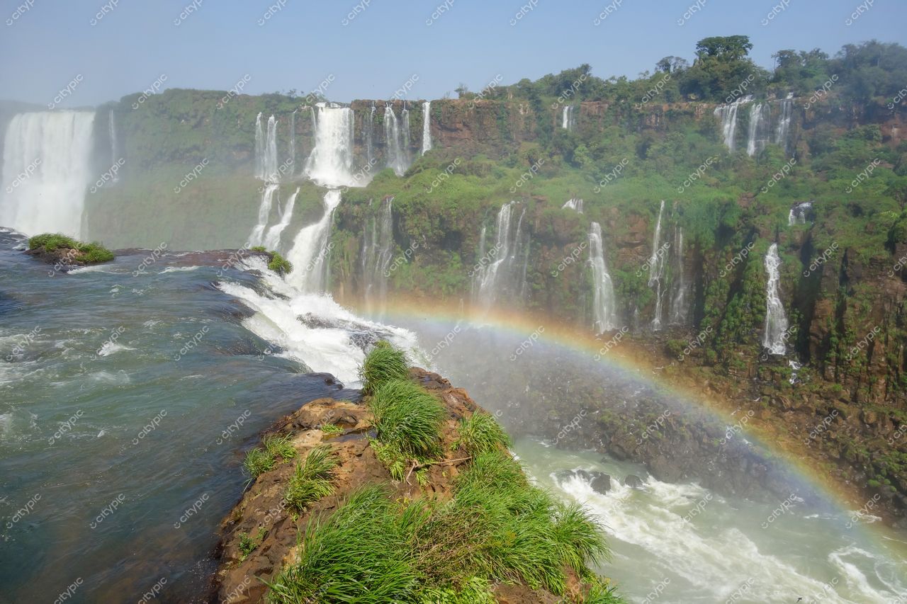 Foz do Iguaçu, Paraná, vista das Cataratas com arco-íris e vegetação densa em dia ensolarado
