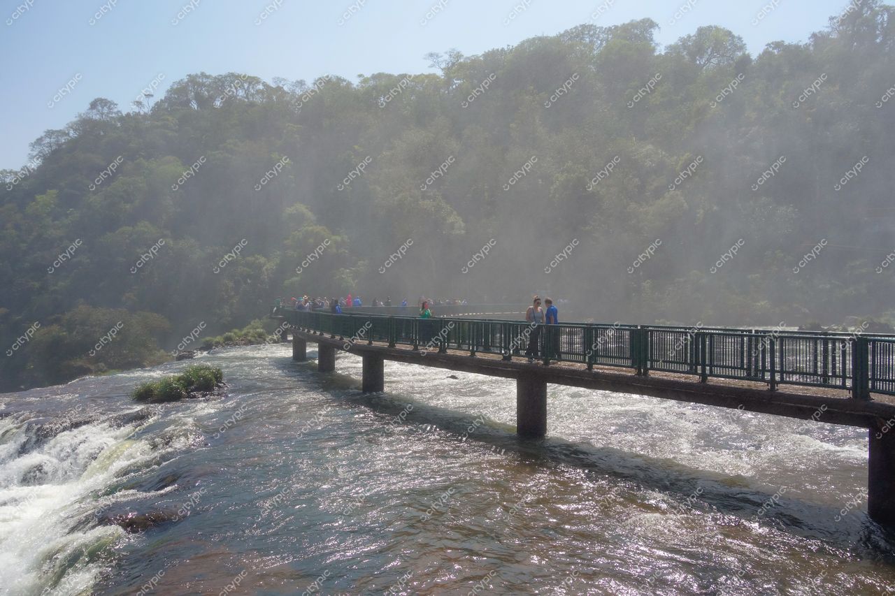 Foz do Iguaçu, Paraná, ponte metálica sobre o Rio Iguaçu com visitantes e vegetação densa ao fundo