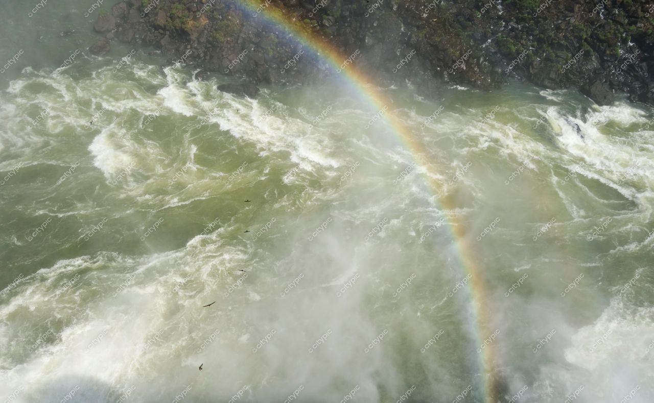 Foz do Iguaçu, Paraná, vista diurna das cataratas com arco-íris e vegetação densa ao redor das águas turbulentas