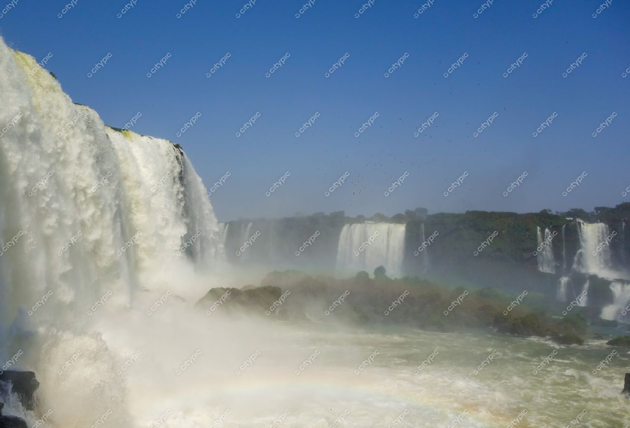 Foz do Iguaçu, Paraná, Cataratas do Iguaçu com forte jato d’água e vegetação exuberante sob céu azul claro