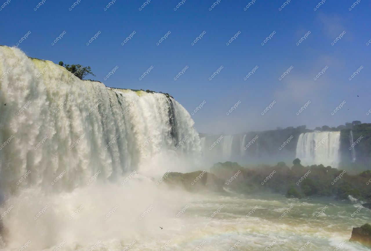 Foz do Iguaçu, Paraná em dia ensolarado com céu azul e vegetação vibrante ao redor das Cataratas do Iguaçu