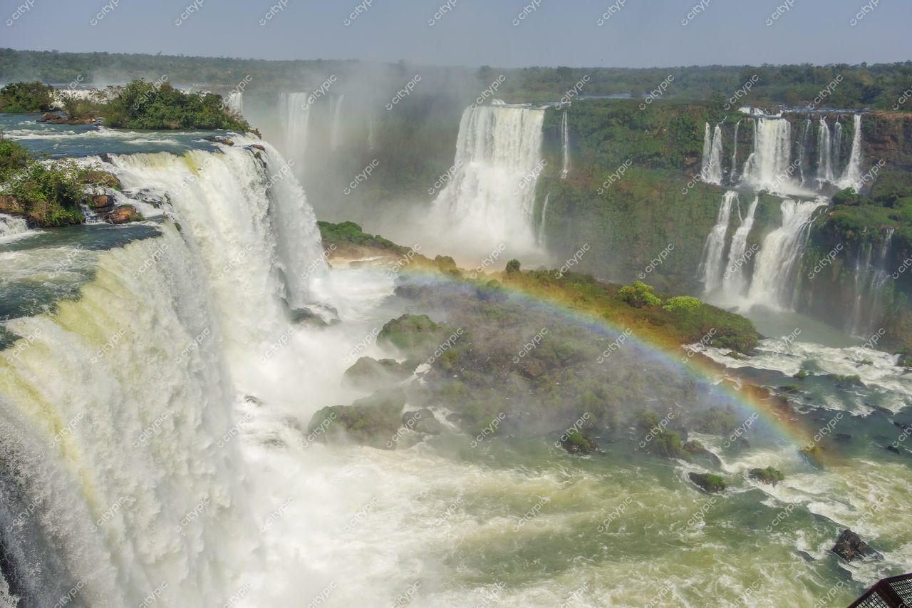 Foz do Iguaçu, Paraná, quedas d’água com arco-íris sob céu claro em dia ensolarado e vegetação exuberante