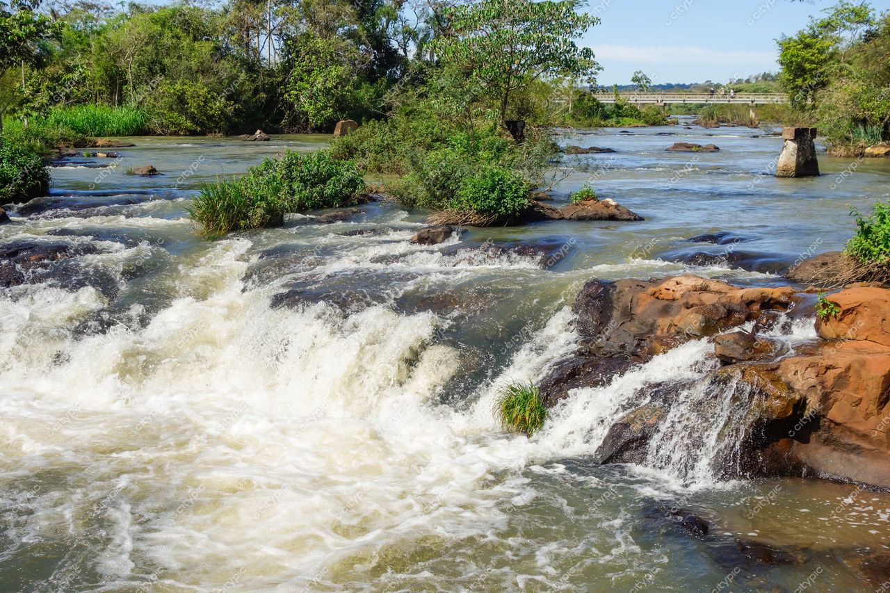 Foz do Iguaçu, Paraná, rio com quedas d’água em dia ensolarado e vegetação densa ao redor das rochas