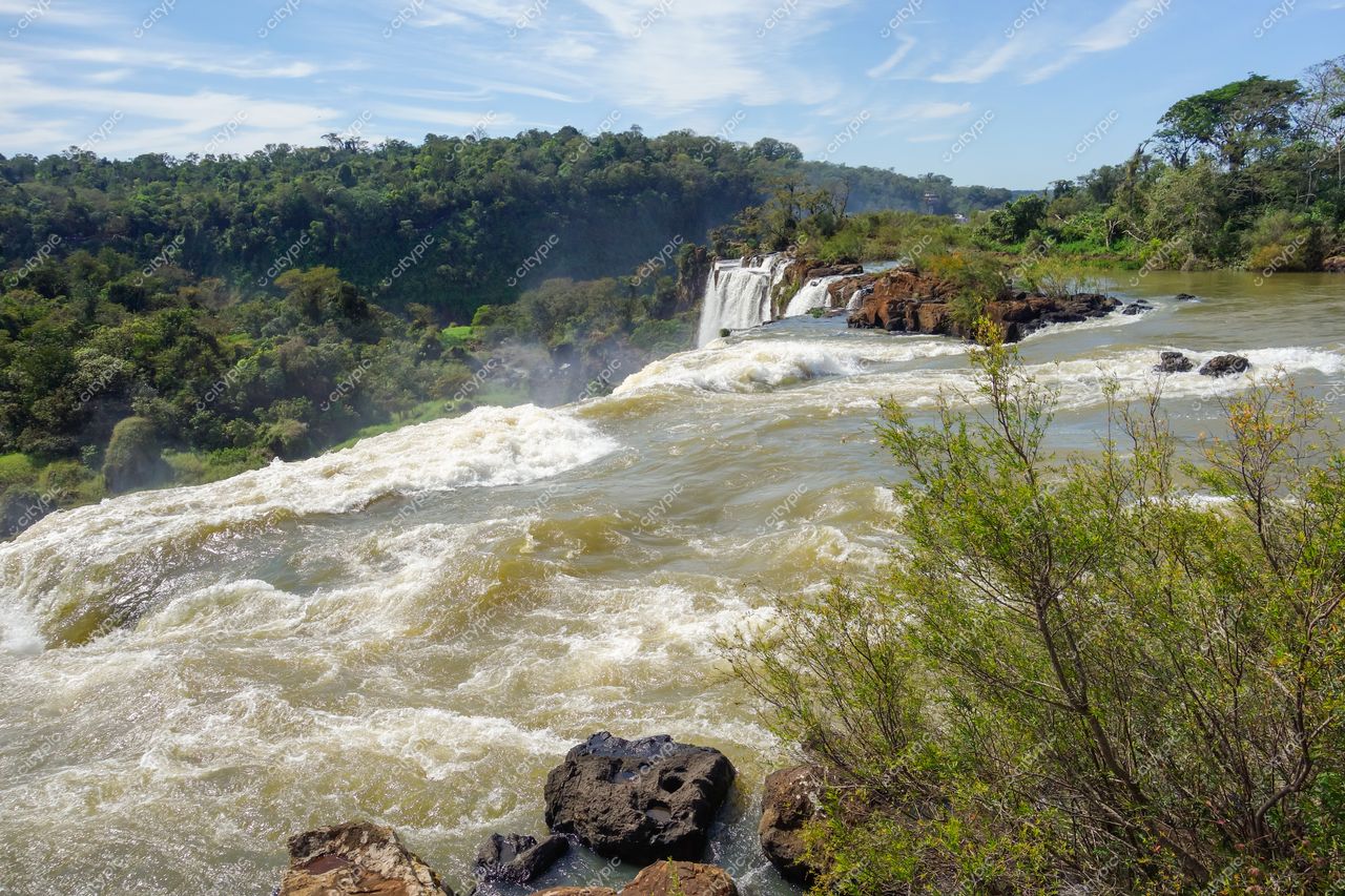 Foz do Iguaçu, Paraná com vegetação densa e luz natural destacando as rochas e o fluxo das cataratas