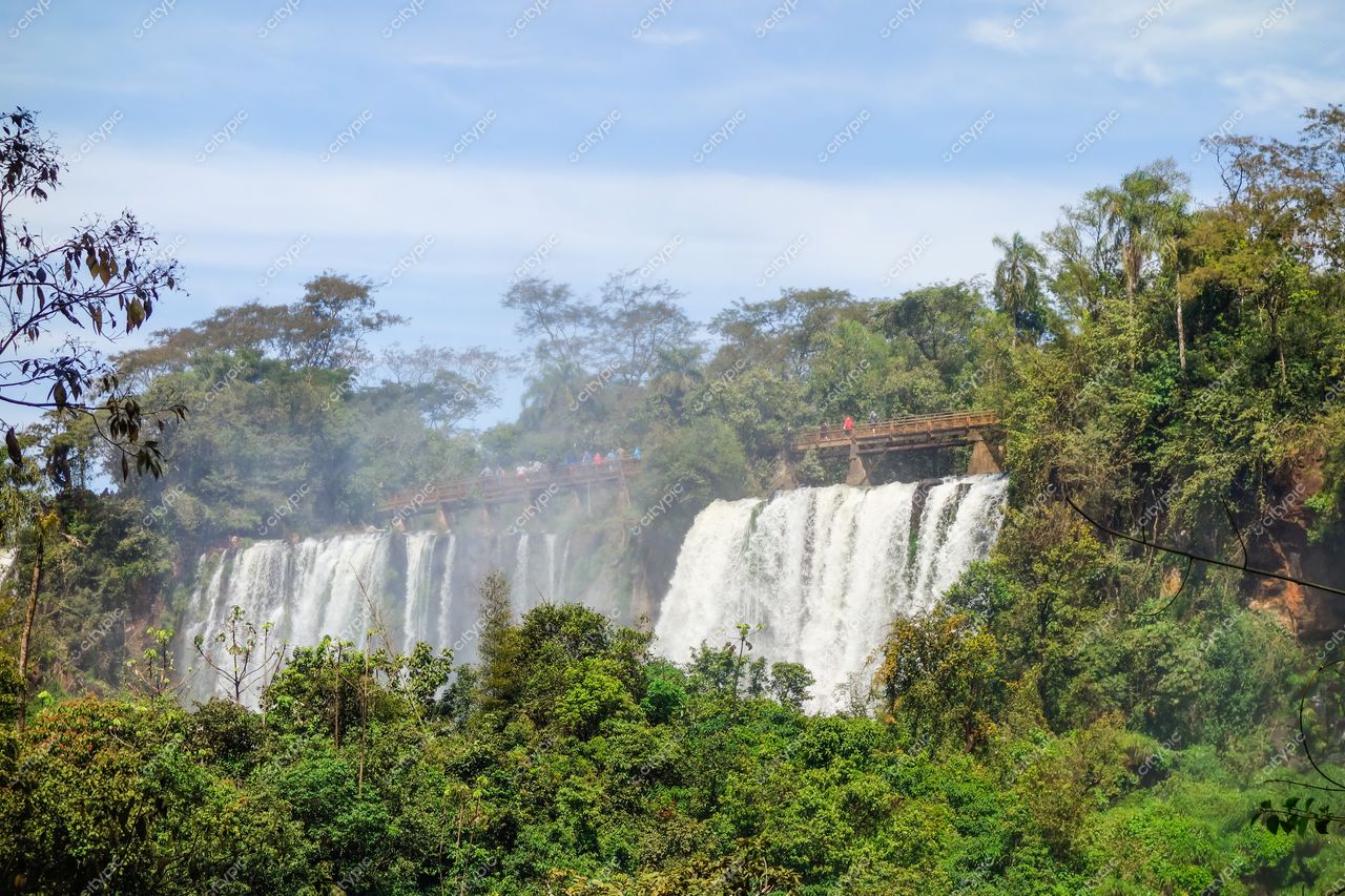 Foz do Iguaçu, Paraná com céu limpo e nuvens esparsas, vegetação densa e passarela de madeira repleta de visitantes
