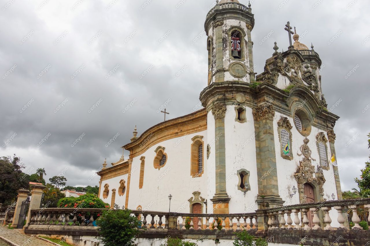 São João del Rei, Minas Gerais, Igreja de São Gonçalo do Amarante em dia nublado com vegetação ao redor e passeio em pedra
