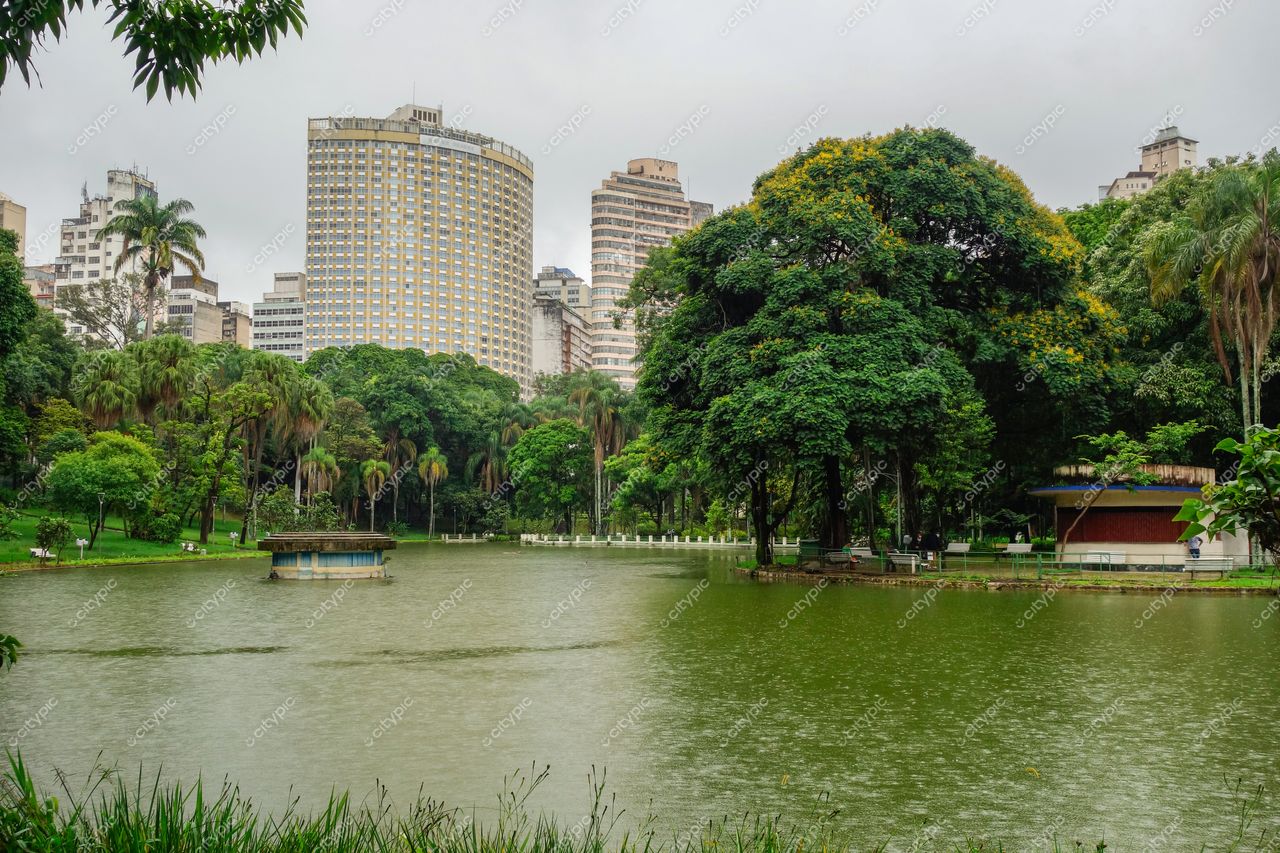 Belo Horizonte, Minas Gerais, parque urbano com lago refletindo edifícios modernos e densa vegetação em dia nublado