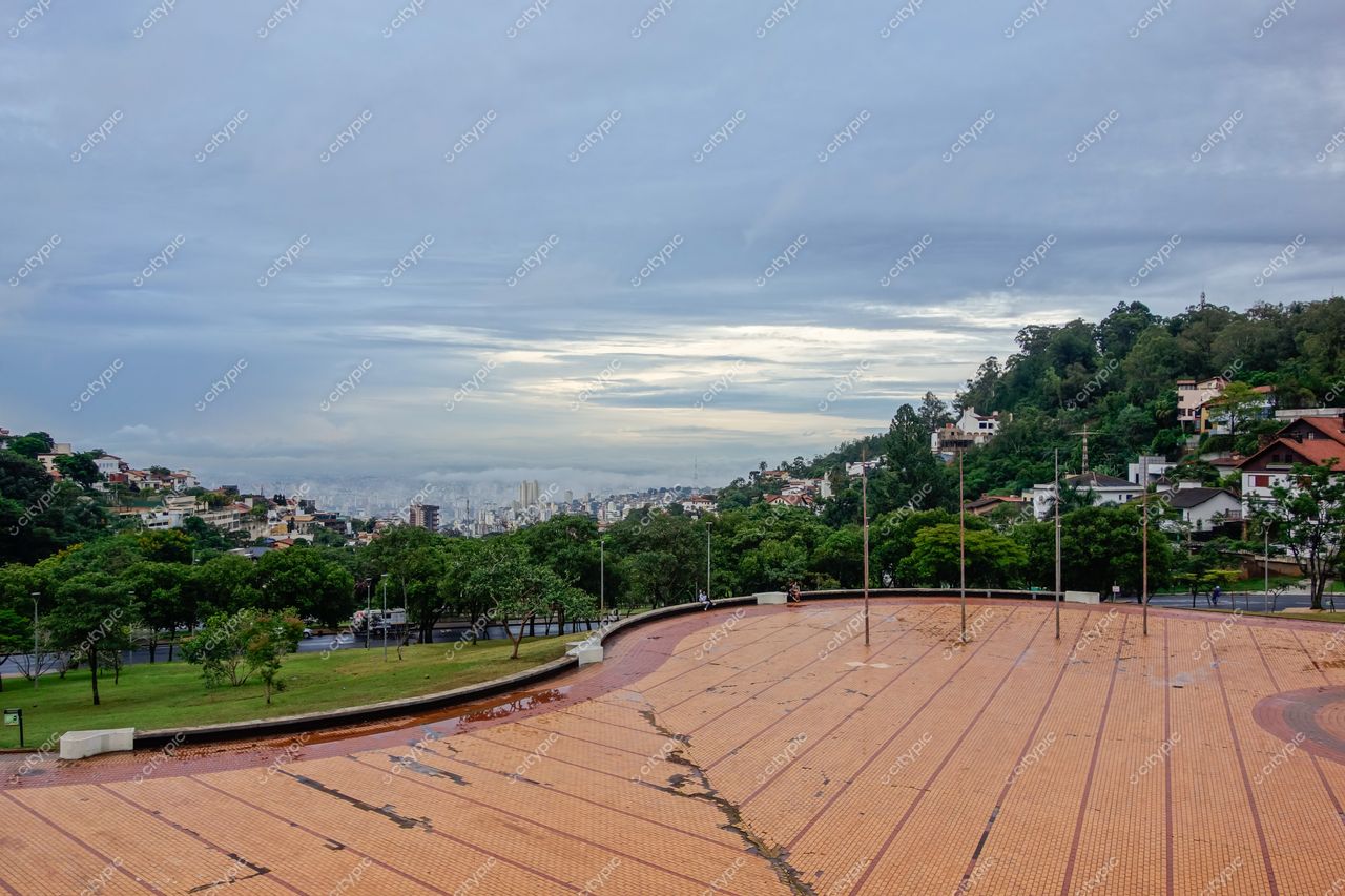 Belo Horizonte, Minas Gerais, vista panorâmica em dia nublado com piso avermelhado e poças d’água no primeiro plano