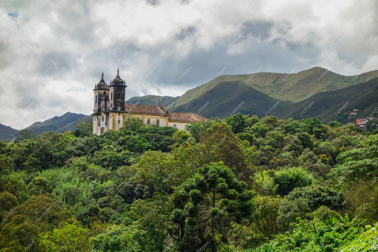 Ouro Preto, Minas Gerais, igreja barroca entre montanhas com vegetação densa e céu parcialmente nublado ao fundo