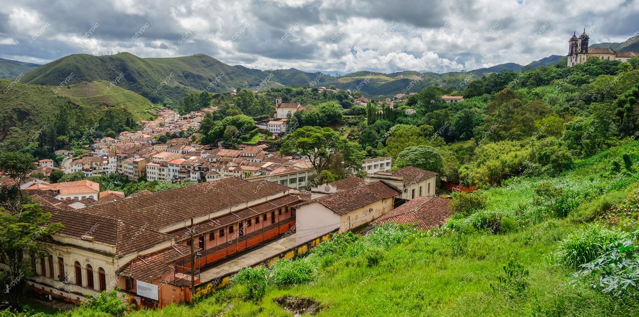 Ouro Preto, Minas Gerais vista panorâmica com arquitetura colonial e vegetação exuberante sob céu nublado e montanhas verdes