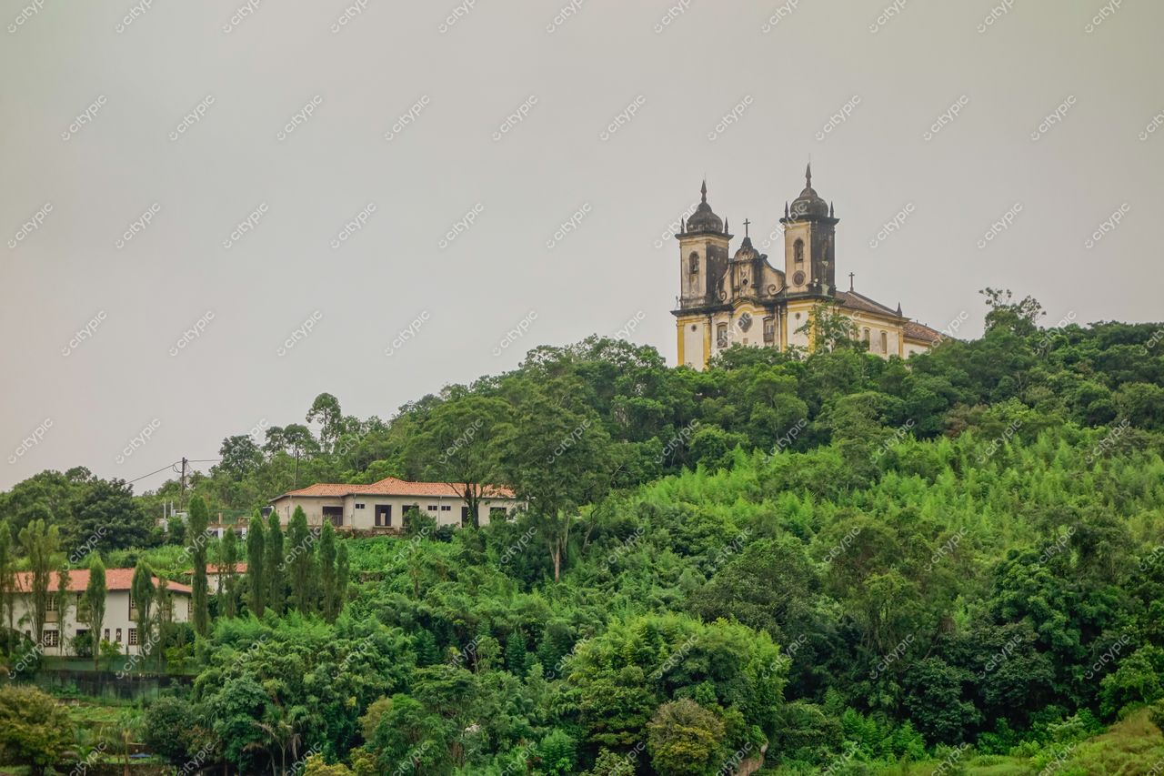 Ouro Preto, Minas Gerais vista da colina com igreja colonial em dia nublado e vegetação densa ao redor