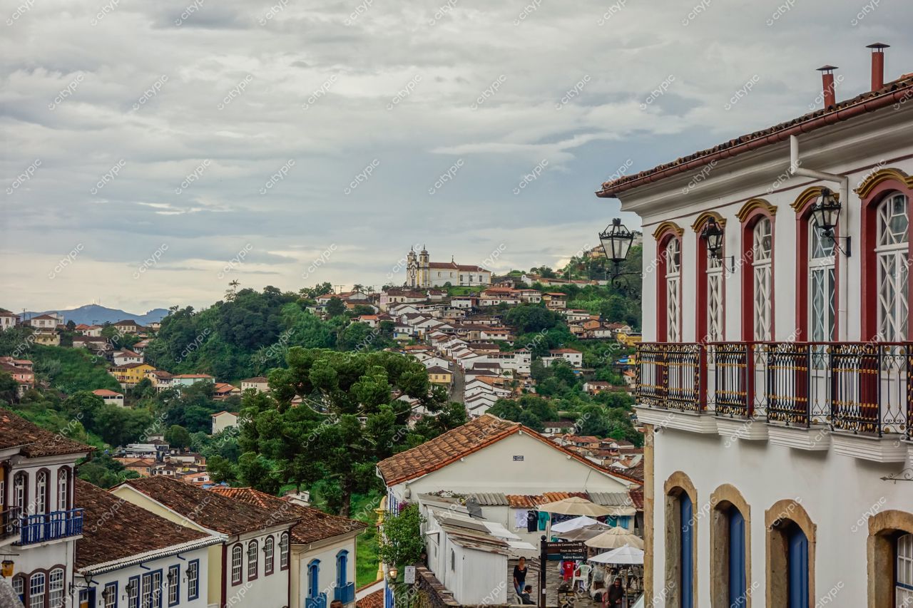Ouro Preto, Minas Gerais vista panorâmica com edifício branco em primeiro plano e vegetação verde sob céu nublado