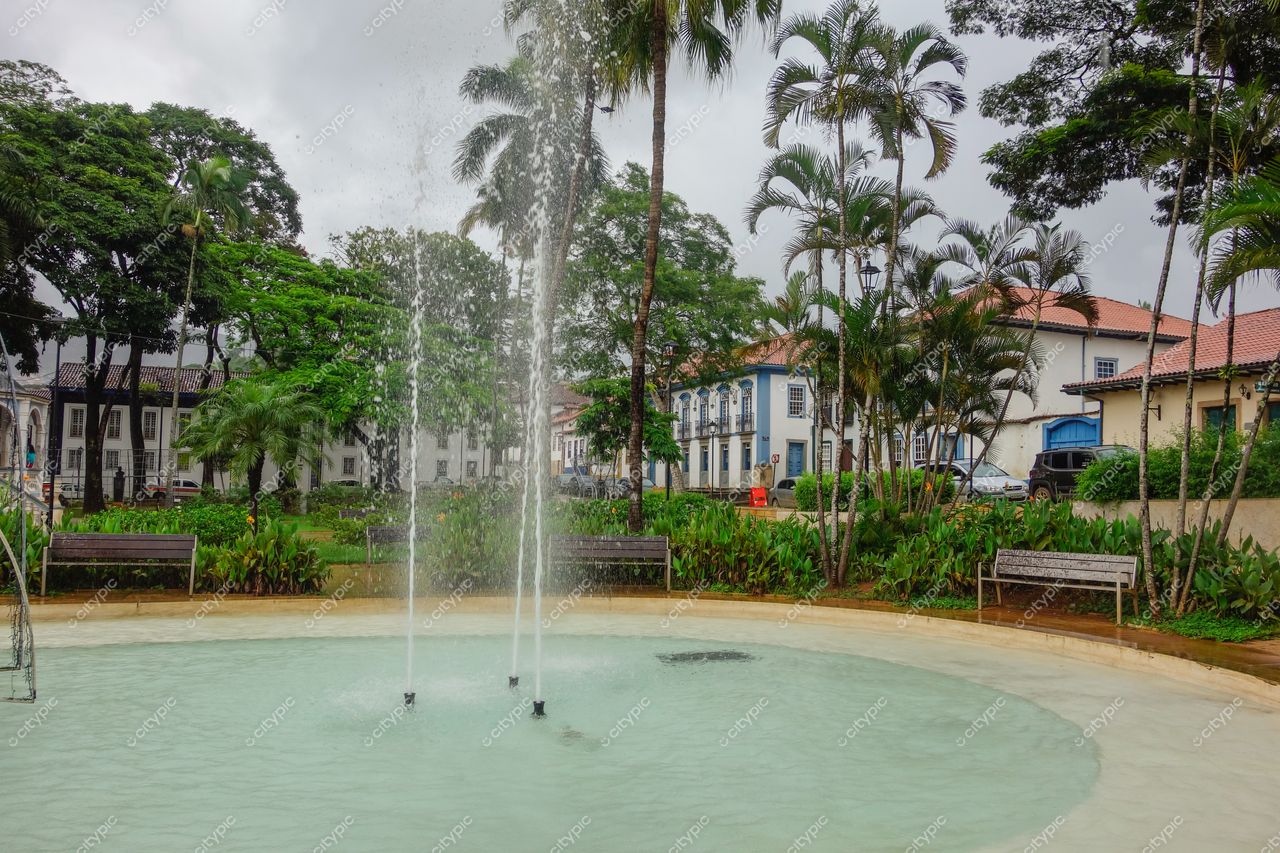 Mariana, Minas Gerais, praça com fonte de água em dia nublado e vegetação densa ao fundo, arquitetura colonial visível