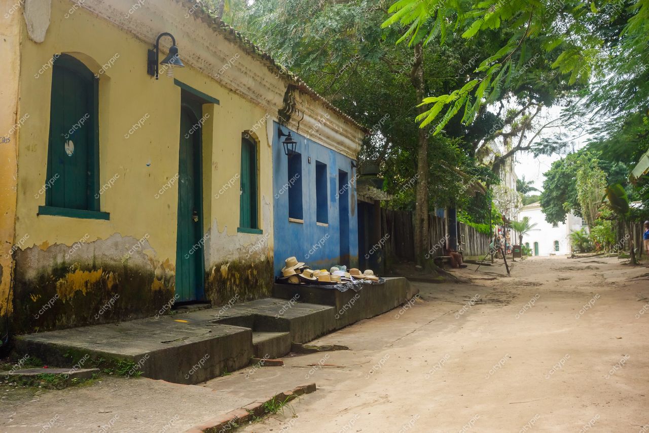Porto Seguro, Bahia, rua tranquila com casas coloniais amarelas e azuis sob iluminação suave em dia nublado