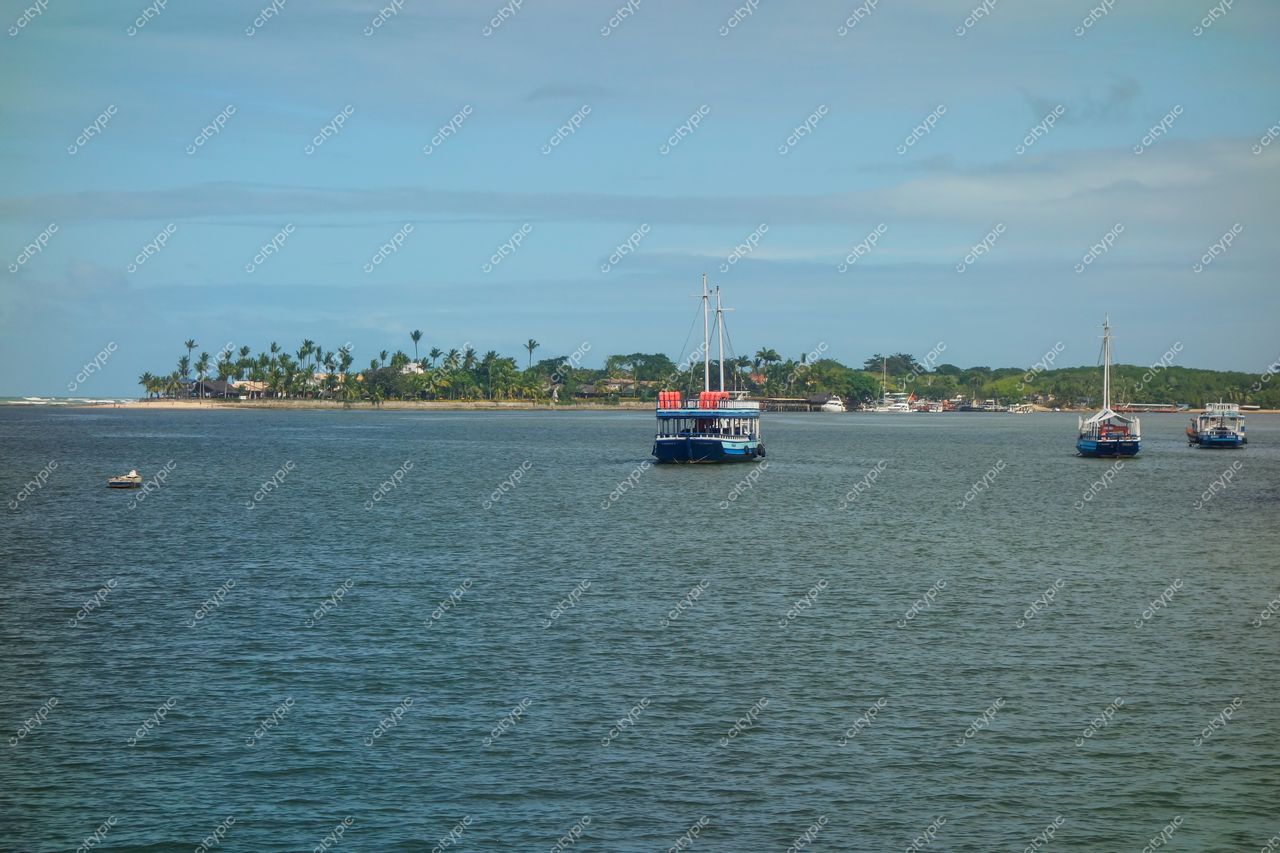 Porto Seguro, Bahia com barcos ancorados em águas calmas e ilha com palmeiras sob céu azul claro