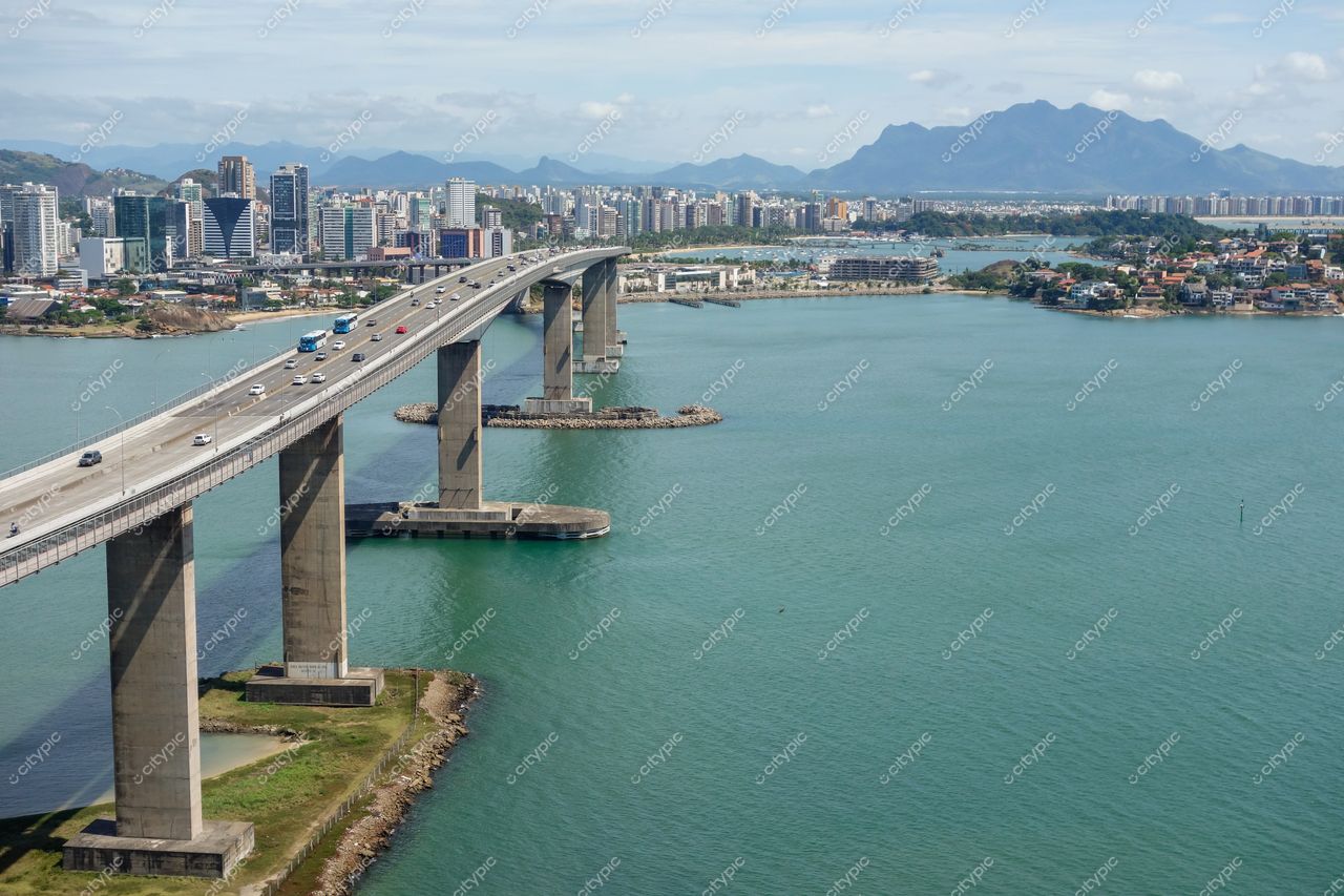 Vitória, Espírito Santo com vista panorâmica da ponte sobre águas calmas e arranha-céus sob céu parcialmente nublado