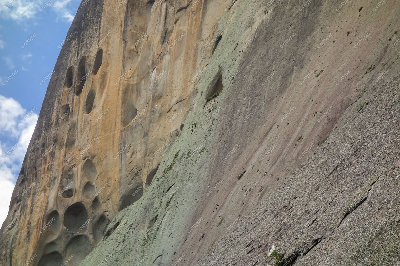 Domingos Martins, Espírito Santo, formação rochosa vertical com tonalidades bege e cinza sob céu azul e vegetação esparsa