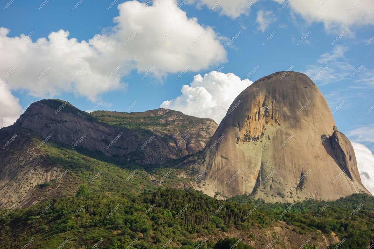 Domingos Martins, Espírito Santo, relevo rochoso vertical com vegetação densa sob céu parcialmente nublado em dia claro
