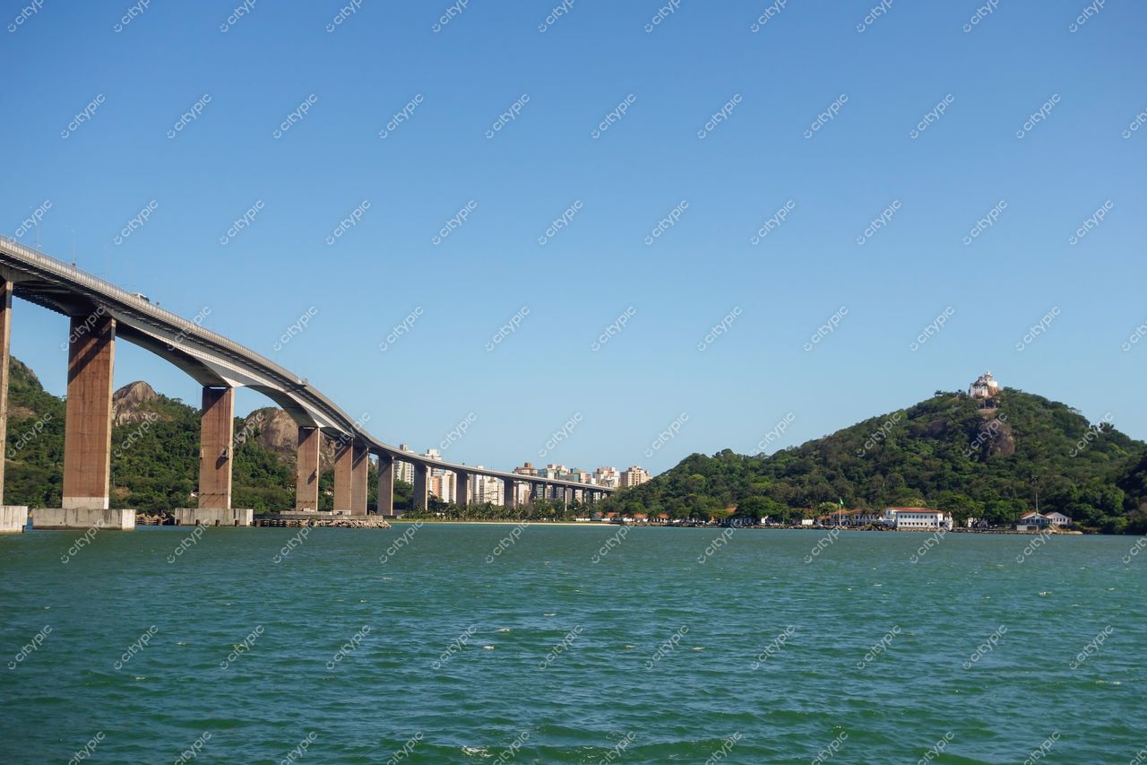 Vitória, Espírito Santo vista do Acesso Norte com ponte sobre água e morro vegetado ao fundo em dia ensolarado