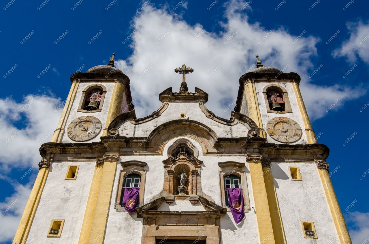 Ouro Preto, Minas Gerais, fachada da Igreja de São Francisco de Assis sob céu azul com nuvens brancas e detalhes em amarelo