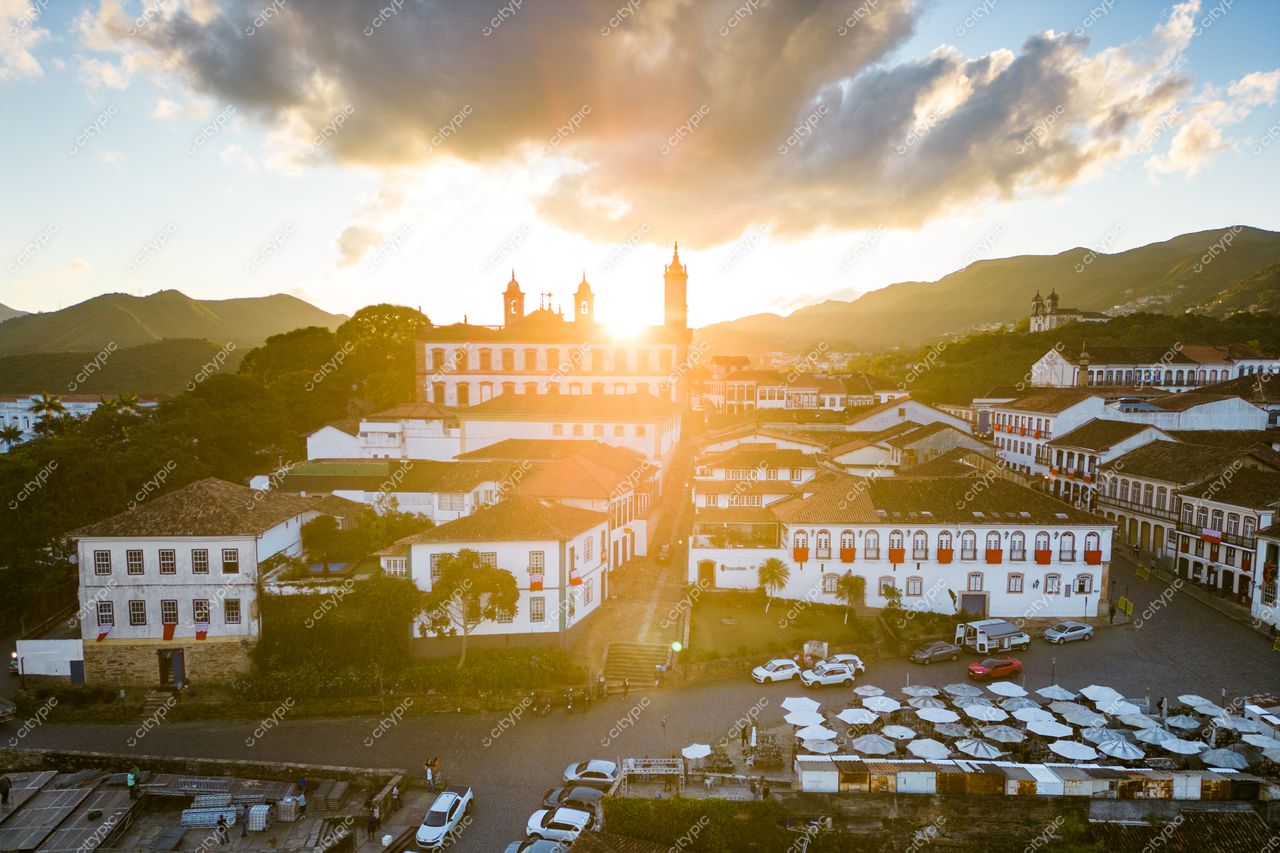 Ouro Preto, Minas Gerais, pôr do sol suave sobre arquitetura colonial com montanhas ao fundo e veículos nas ruas de paralelepípedos