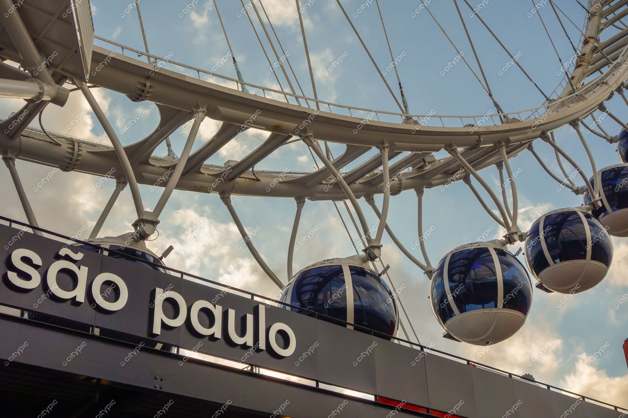 Roda Rico em São Paulo com cabines esféricas e arquitetura moderna sob céu claro e nuvens dispersas