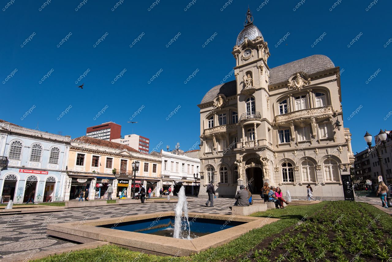 Curitiba, Paraná vista da Praça Tiradentes com fonte borbulhante, céu azul e arquitetura histórica ao fundo