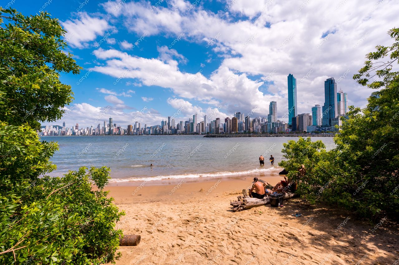 Balneário Camboriú, Santa Catarina, vista da praia com arranha-céus ao fundo e céu azul com nuvens brancas
