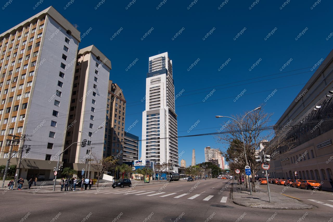 Curitiba, Paraná em dia ensolarado com edifícios variados e moderna construção alta ao fundo em rua movimentada