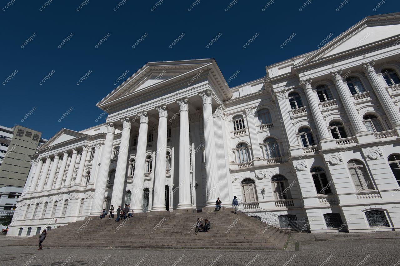 Curitiba, Paraná, fachada neoclássica de edifício histórico em dia ensolarado com pessoas nas escadas e ambiente moderno