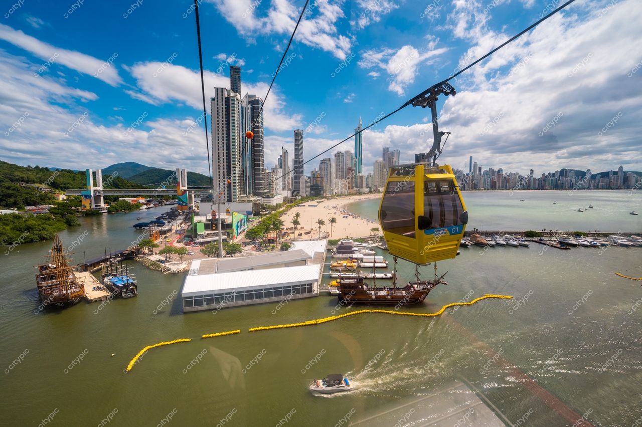 Balneário Camboriú, Santa Catarina com teleférico amarelo em primeiro plano e edifícios à beira-mar sob céu nublado