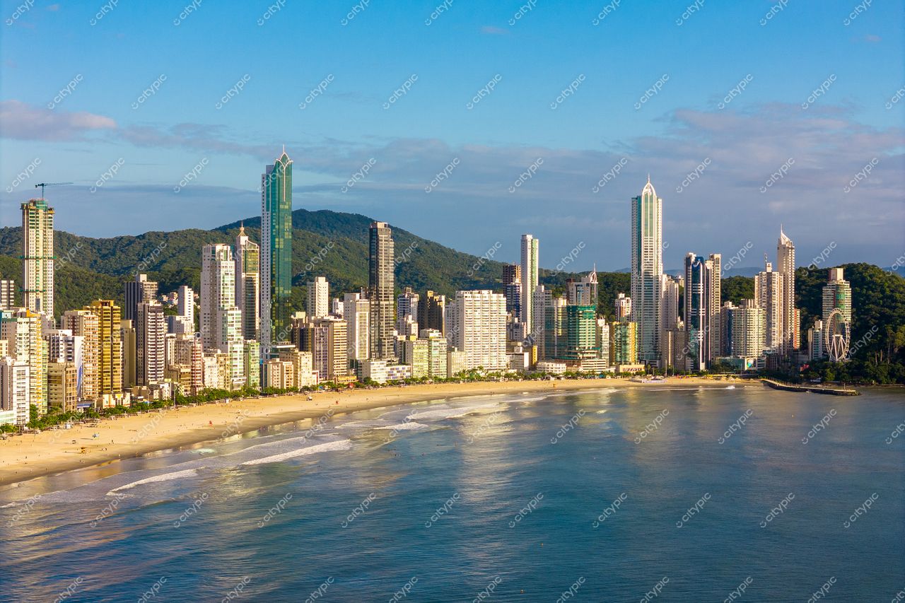 Balneário Camboriú, Santa Catarina, orla com arranha-céus modernos refletindo luz do sol pela manhã e vegetação montanhosa