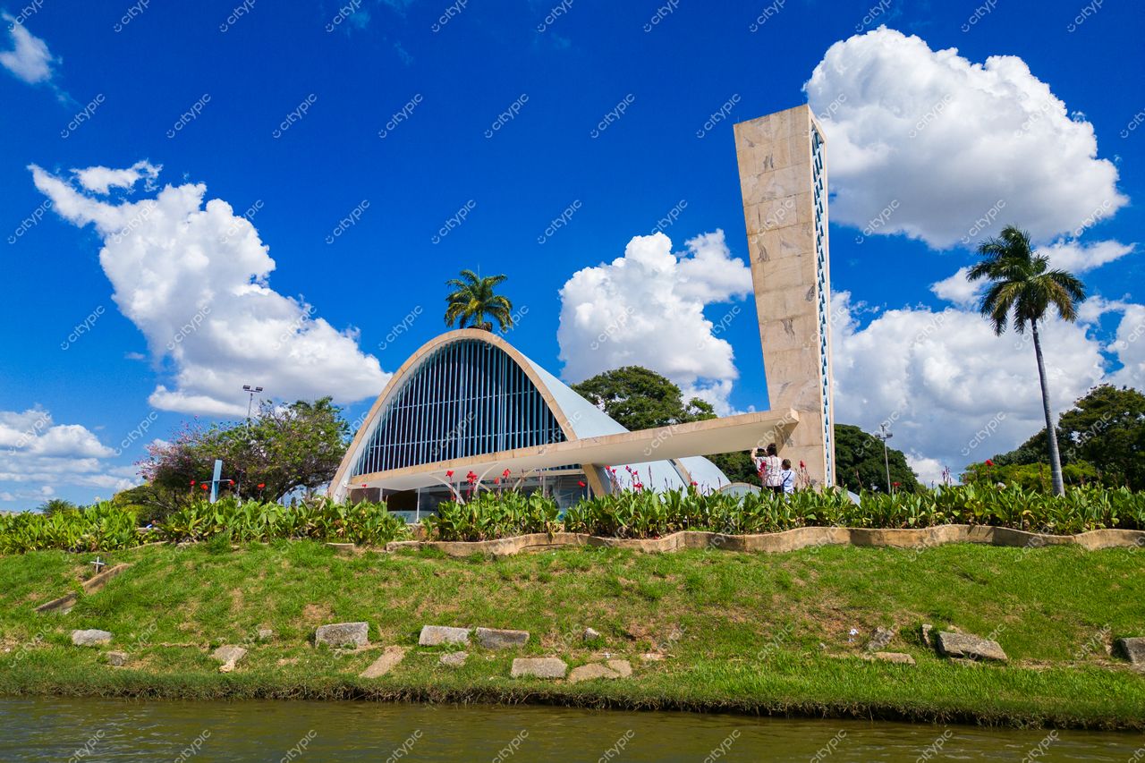 Belo Horizonte, Minas Gerais, edifício moderno com telhado curvo e torre vertical em dia ensolarado com vegetação verde