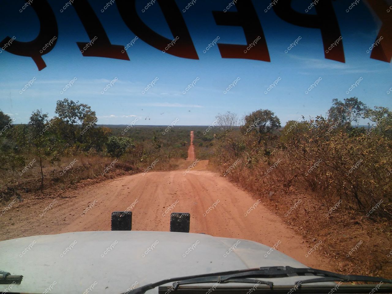 Jalapão, Tocantins, estrada de terra empoçada vista do interior de veículo sob céu claro e vegetação xerófila