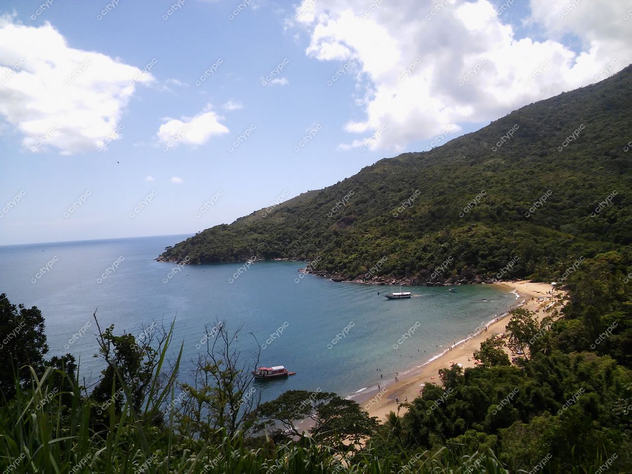 Ilhabela, São Paulo vista panorâmica da costa em dia ensolarado com praia clara e vegetação densa ao fundo