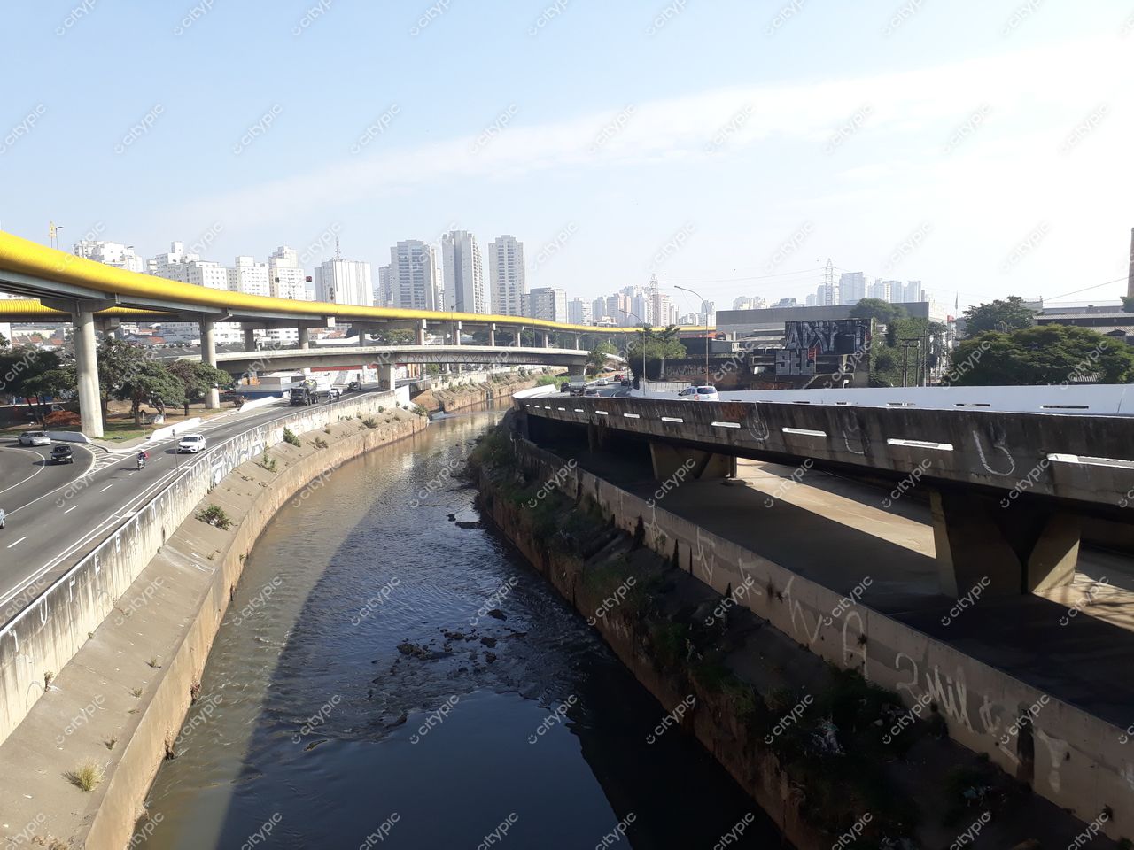 São Paulo, São Paulo, vista urbana em dia ensolarado com arranha-céus e canal entre pistas de tráfego