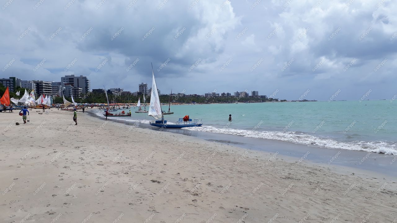 Maceió, Alagoas com praia de areia clara e prédios ao fundo em tarde nublada e tranquila com veleiros
