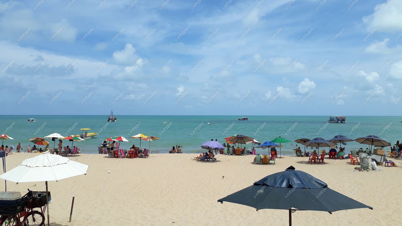 João Pessoa, Paraíba, praia com areia clara e fina, pessoas sob guarda-sóis coloridos em dia ensolarado