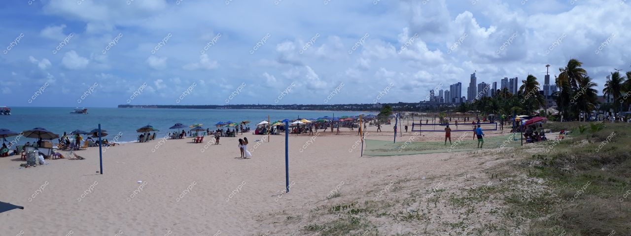 João Pessoa, Paraíba, praia com céu parcialmente nublado e pessoas sob guarda-sóis coloridos praticando esportes na areia clara
