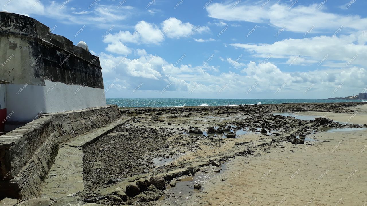 Natal, Rio Grande do Norte, forte de pedra à esquerda com maré baixa e céu claro em dia ensolarado