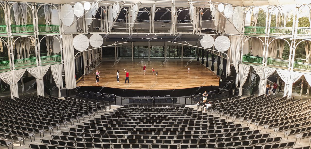 Ópera de Arame em Curitiba com palco de madeira, estrutura metálica e vegetação ao fundo em dia ensolarado