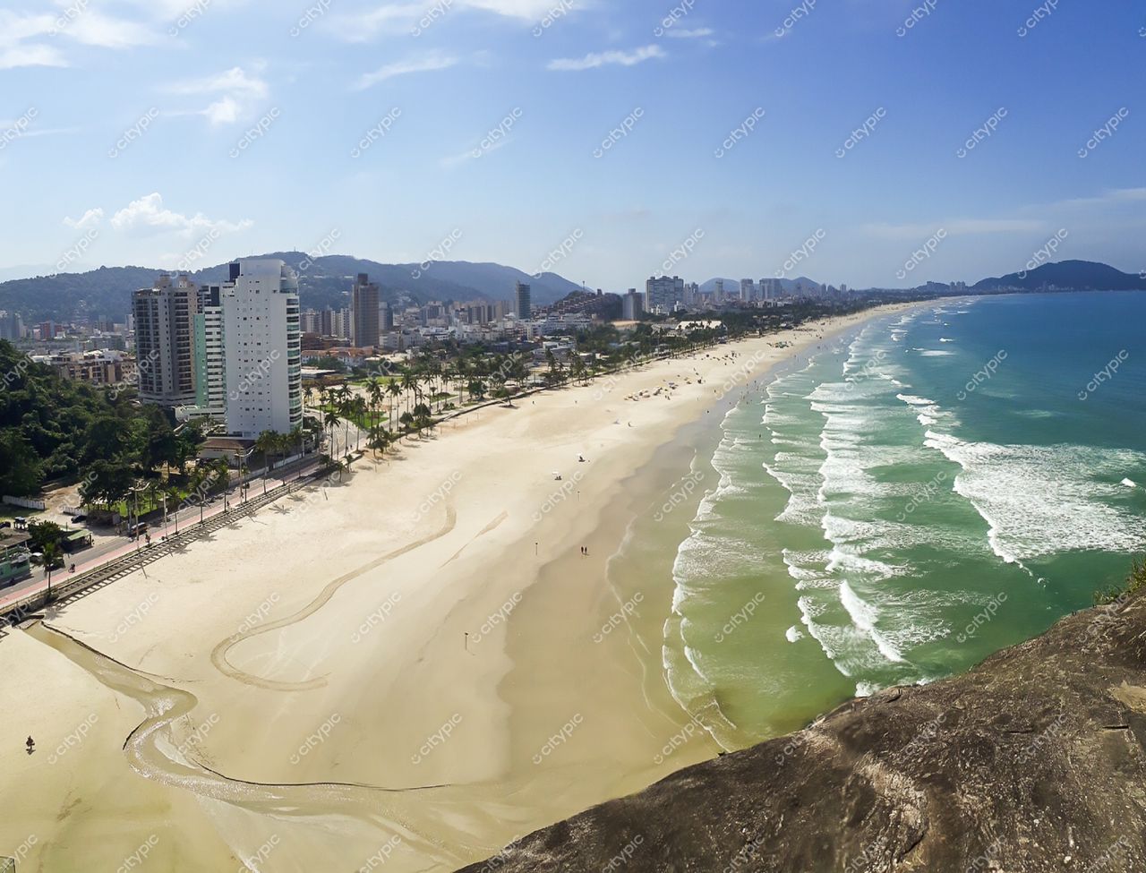 Guarujá, São Paulo vista panorâmica da praia em dia ensolarado com edifícios modernos e palmeiras na orla