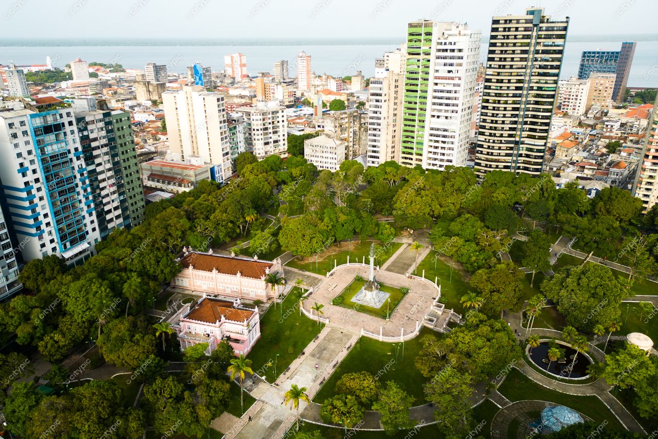 Belém, Pará vista aérea de parque urbano com vegetação densa e edifícios modernos ao fundo em luz suave da tarde