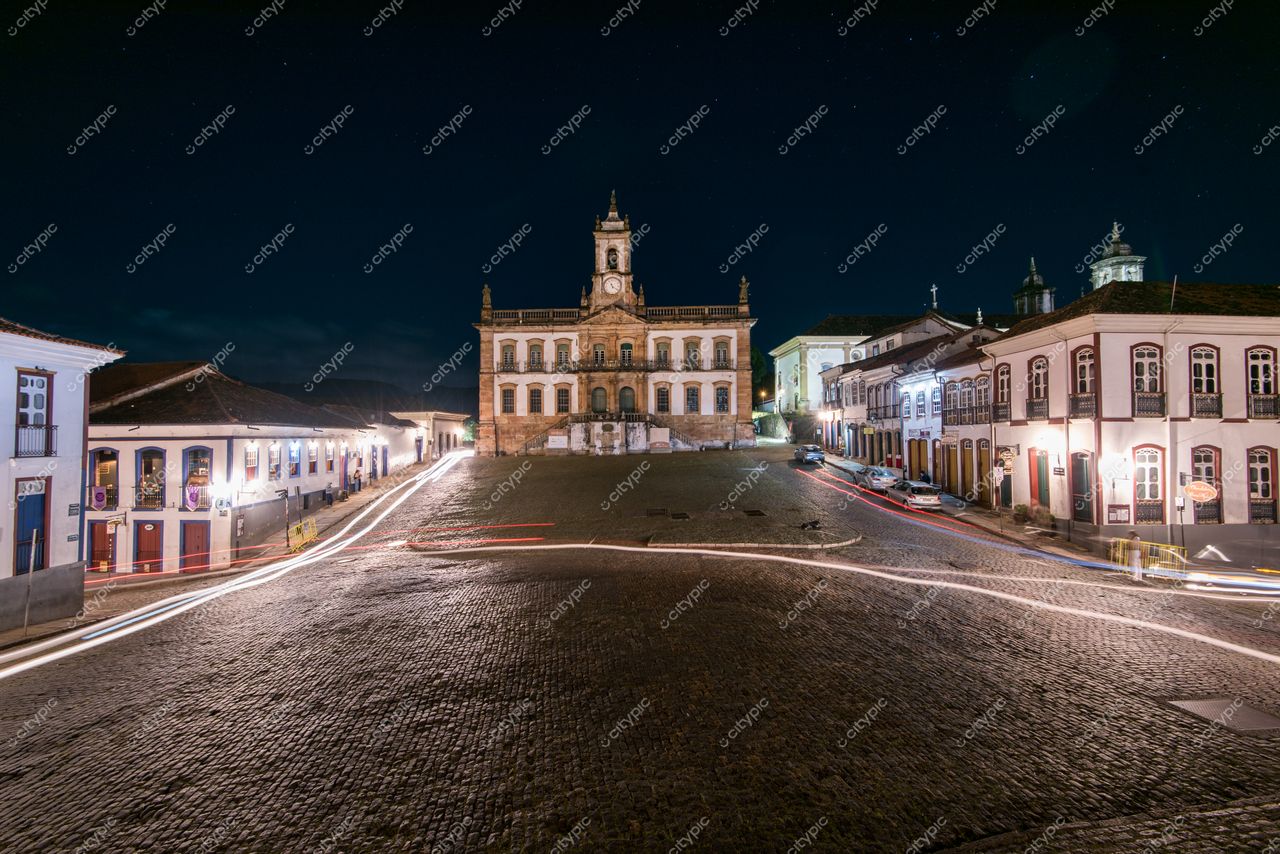 Ouro Preto, Minas Gerais vista noturna da Praça Tiradentes com iluminação de veículos e céu estrelado ao fundo
