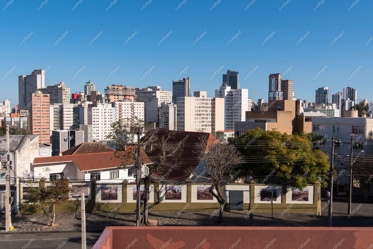 Curitiba, Paraná vista panorâmica com edifícios variados, céu azul e área residencial com casas de telhado vermelho