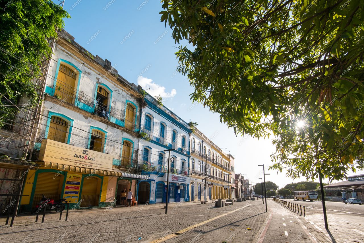 Belém, Pará, rua tranquila com edificações históricas azuis e brancas sob luz suave e sombras de árvores